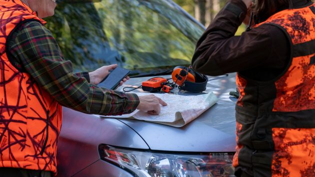 Kaksi ihmistä tutkii karttaa auton konepellillä.