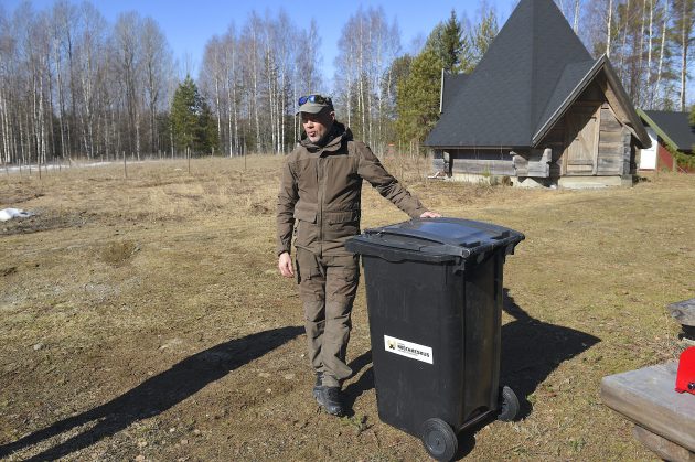 En man lutar sig mot en soptunna. I bakgrunden finns ett vindskydd.